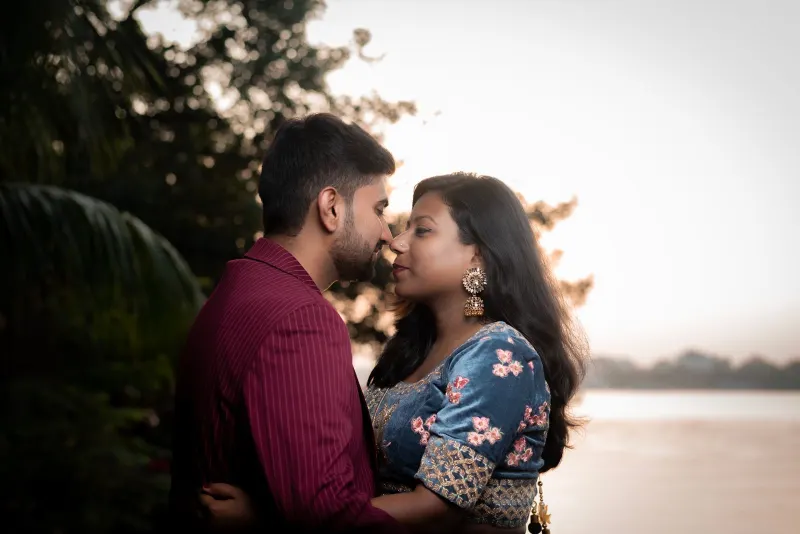 Indian couple share a close, tender moment by a river at golden sunset
